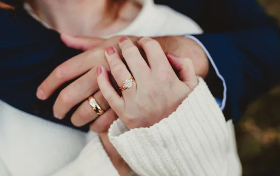 Engagement ring and wedding band on hand of man and woman close up